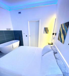 1 dormitorio con cama blanca y bañera en The Apartment, en Porto Santo Stefano
