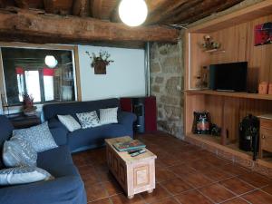 a living room with a blue couch and a tv at La Casa de las rocas - Ribeira Sacra in Rubiacós