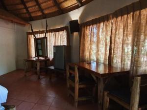 a dining room with a table and a television and curtains at KaMsholo Bushveld Safaris 