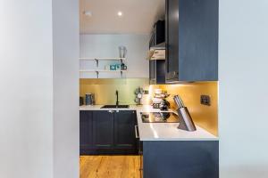 ロンドンにあるStunning Modern Apartment in the Heart of Holbornのキッチン(黒いキャビネット、白いカウンタートップ付)