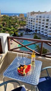 una mesa con copas de vino y un bol de fruta en el balcón en Blue Cristianos by W Tenerife, en Los Cristianos