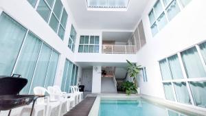 an indoor pool in a building with white chairs at The Inn10 Pool Villa Pattaya, Entire Villa, 9 Bedrooms, Private Indoor Swimming Pool, ดิ อินน์เท็น in Pattaya Central