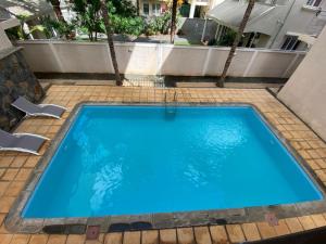 a large blue swimming pool with two chairs and a building at Le Nid Flic en Flac in Flic-en-Flac