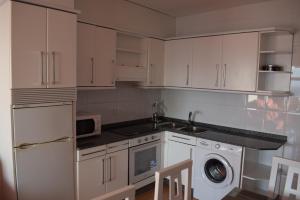 a kitchen with white cabinets and a sink and a dishwasher at Apartamento a pie de playa en As Sinas. in Villanueva de Arosa +1 photo