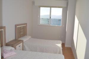 a small room with two beds and a window at Apartamento a pie de playa en As Sinas. in Villanueva de Arosa