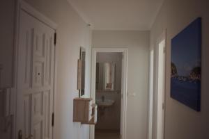 a hallway with a bathroom with a sink and a mirror at Apartamento a pie de playa en As Sinas. in Villanueva de Arosa