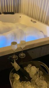 two glasses of wine next to a bath tub at FIKA Residence in Dois Irmãos