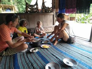 Eine Gruppe von Menschen, die auf dem Boden sitzen und Essen essen. in der Unterkunft Arnolds Familly homestay in Bajawa