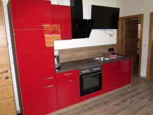 a red kitchen with a sink and a stove at Ferienhaus Friedle in Leogang