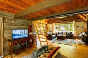 sala de estar con escalera, TV y sofá en Elk Meadows Cottage, en Packwood