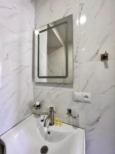 une salle de bain blanche avec un lavabo et un miroir dans l'établissement Premium Apartment Tamarioni, à Tbilissi 9 autres photos