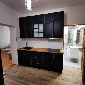 a kitchen with black cabinets and a sink at Apartament Zielony in Włodawa