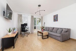 sala de estar con sofá gris y escritorio en Pleasant Apartment with Terrace Cracow by Renters, en Cracovia