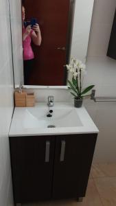 une femme prenant une photo d'un lavabo de salle de bain avec un miroir dans l'établissement Apartamento Los Padrinos, à Cordoue