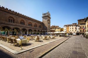 a street with tables and chairs and a clock tower at Grace apartment - Smart Holiday in Mantova