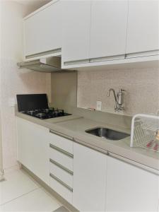 a kitchen with white cabinets and a sink at Aconchego in Maringá