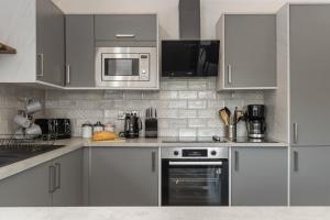 Willow Cottage في تينبي: مطبخ بدولاب بيضاء وموقد وميكروويف