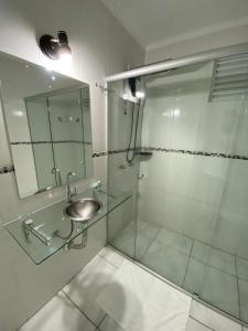 a bathroom with a shower with a sink and a mirror at Hayer Hotel in Erechim