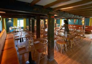 a woman standing in a restaurant with tables and chairs at Sculthorpe Mill in Fakenham