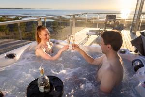 Marina Resort A7 في كالايوكي: رجل وامرأة في حوض استحمام ساخن مع المشروبات