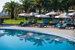 a swimming pool with blue chairs and umbrellas at Iberostar Bellevue All Inclusive in Budva