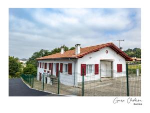 Casa blanca con ventanas rojas y valla en Gure Chokoa en Bardos