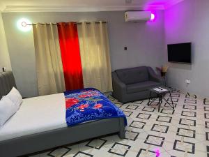 a bedroom with a bed and a chair and a television at Bonsukoda Lodge in Accra