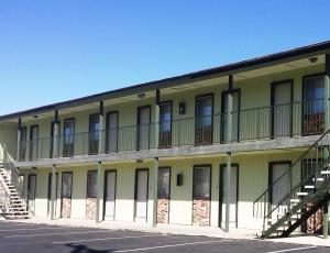 un bâtiment jaune avec des balcons et des escaliers dans un parking dans l'établissement El Portal Motel, à Beatty