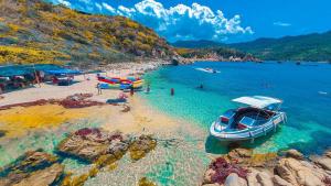 a boat on a beach with people in the water at Thao Nguyen Homestay in Thôn Mỹ Phước