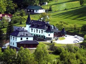 a large white building with black roofs on a hill at Hotel Zlatý Orel in Ostravice