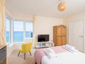 a bedroom with a bed and a tv and windows at Glas Mordros in St Ives