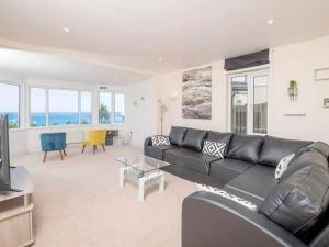 a living room with a black couch and a television at Glas Mordros in St Ives +1 photo