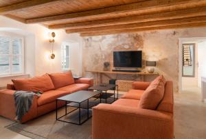 ein Wohnzimmer mit zwei orangenen Sofas und einem TV in der Unterkunft Dvor Pitve Villas in Jelsa
