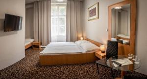 プラハにあるHotel Brixenのベッドと鏡が備わるホテルルーム