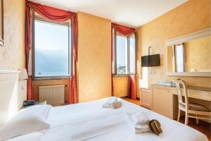 a bedroom with a bed and a desk and windows at Hotel Le Palme in Limone sul Garda
