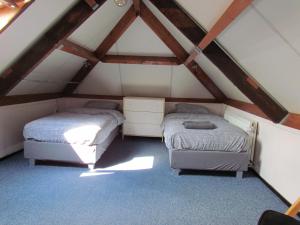 two beds in a attic room with wooden beams at Bed & Breakfast Hillegom in Hillegom