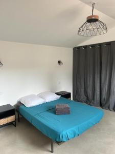 um quarto com uma cama com um cobertor azul em La Massoterie gîte 3 em Théza