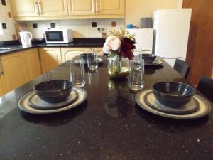 eine Küche mit einem Tisch mit Tellern und Blumen darauf in der Unterkunft Gainford House in Walsgrave on Sowe