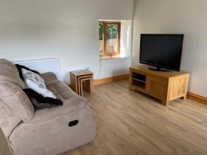 a living room with a couch and a flat screen tv at Red Kite Barn in Ammanford