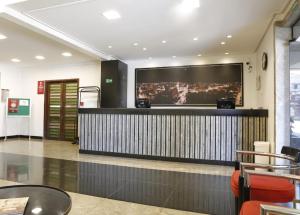 a lobby with a bar with a large screen at Hz Hotel in Patos de Minas