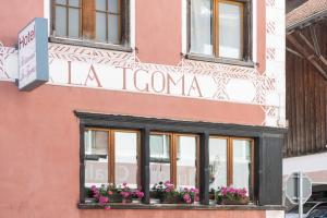 ein Schild an der Seite eines Gebäudes mit Blumen im Fenster in der Unterkunft La Tgoma - Hotel & Restaurant in Lenz