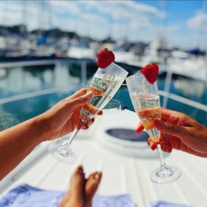 利明頓的住宿－Y-Knot-Two Bedroom Luxury Motor Boat In Lymington，两人在船上拿着香槟杯和草莓