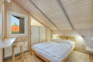 uma cama num pequeno quarto com uma janela em Kranich Ferienhäuser mit Innenpool em Hohendorf