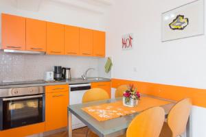 una cucina con armadi arancioni, tavolo e sedie di Valentina Apartment and Studio a Vantačići