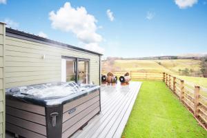 bañera de hidromasaje en la cubierta de una casa en Shiphorns luxury cabin with a hot tub en Eddleston