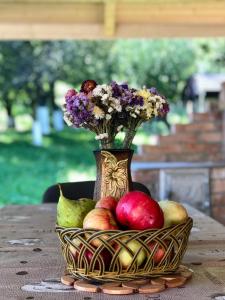 um vaso cheio de flores e uma cesta de frutas em Pensiunea Bucur em Dămuc