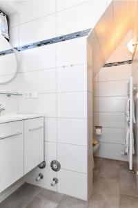 La salle de bains blanche est pourvue d'un lavabo et d'un miroir. dans l'établissement Ferienwohnung Seepferdchen im Wohnpark Werdum, à Werdum
