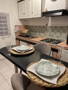a kitchen with a table with two plates and wine glasses at OSun Bungalow in Saint-Leu