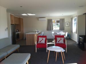 Il comprend un salon avec des chaises rouges et une cuisine. dans l'établissement Matagouri Cottage - Lake Tekapo, à Lac Tekapo
