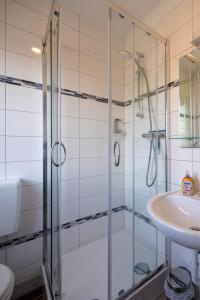 uma casa de banho com um chuveiro e um lavatório. em Gästehaus Olympia Wilhelmshaven - Moderne Einzelzimmer mit eigenem Bad für Monteure em Schortens